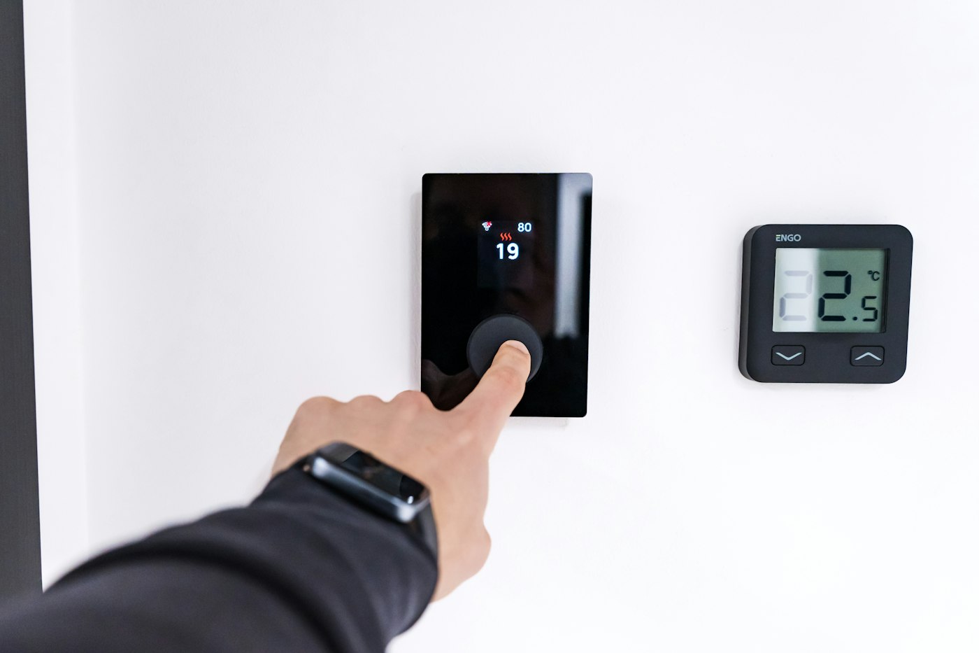 Hand adjusting a digital thermostat as part of a winter home checklist